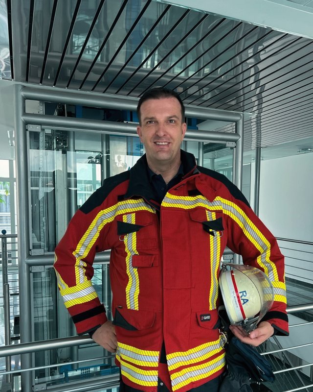 Thomas Knecht in Feuerwehr-Überjacke, den Helm unter dem Arm